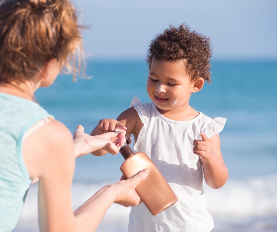 Mom applying sunscreen on young daughter